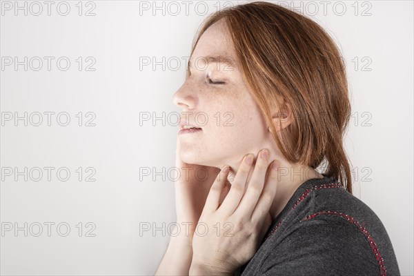 Beauty face. Smiling red haired woman touching healthy skin. Beautiful happy model with moisturized shiny fresh facial skin on white background in studio