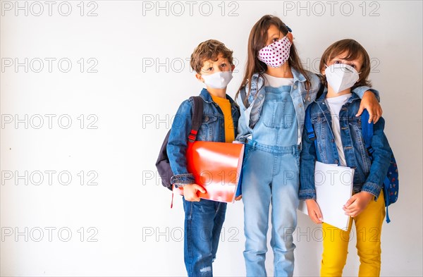 Three children with face masks ready to go back to school. New normality