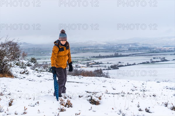 Young girl in yellow jacket playing in the snow with an umbrella. Snow in the town of Opakua near Vitoria in Araba