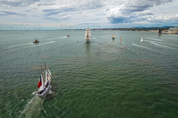 Aerial drone view of tall ships with sails sailing in Tagus river towards the Atlantic ocean in Lisbon