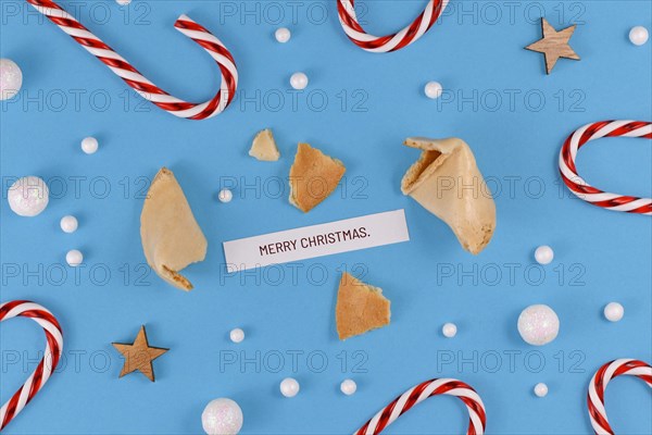 Christmas greetings with open fortune cookie and text 'Merry Christmas' on blue background with candy canes