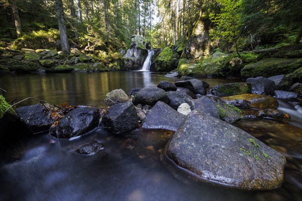 Waterfall in autumn forest with rocks