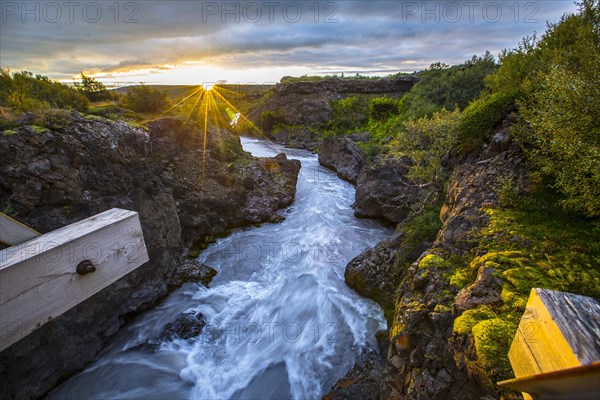 Gorgeous sunset on the wooden bridge of the Barnafoss river