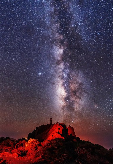 Silhouette of a young man under the stars looking at the lactea way of the Caldera de Taburiente near the Roque de los Muchahos on the island of La Palma