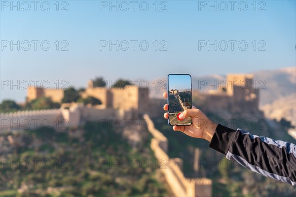 A young tourist taking a photo at the viewpoint of Cerro San Cristobal de la Muralla de Jairan and the Alcazaba in the town of Almeria