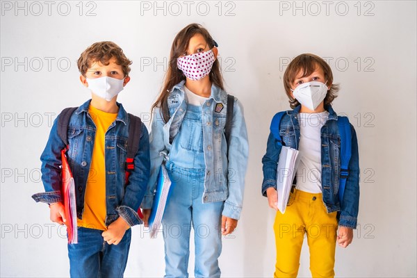 Three children with face masks ready to go back to school. New normality