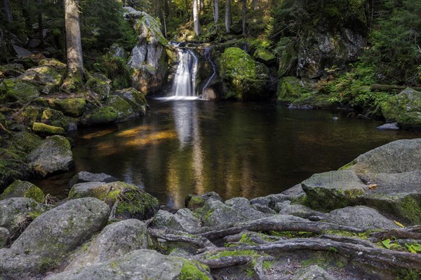 Waterfall in autumn forest with rocks