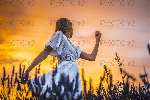 A young blonde Caucasian woman in a white dress in a cultivated lavender field in Navarra