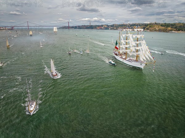 Aerial drone view of tall ships with sails sailing in Tagus river towards the Atlantic ocean in Lisbon
