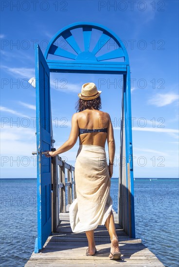 A young brunette passing a blue door in the Caribbean Sea on Roatan Island. Honduras