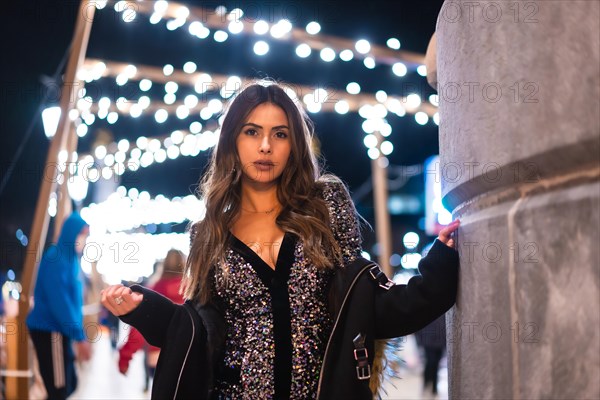 Christmas lifestyle. Portrait of a young brunette Caucasian woman in a fashionable dress with sequins