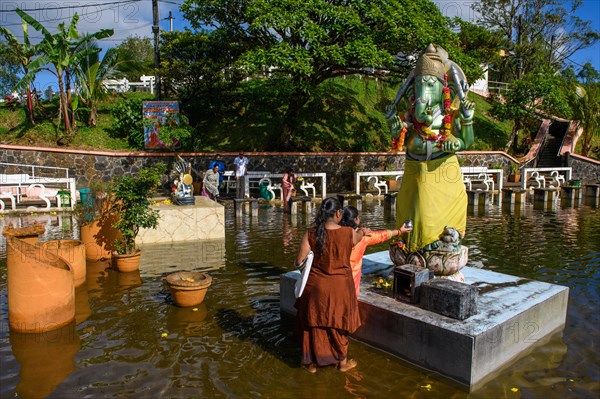 Woman in traditional Indian dress standing in Sacred Lake offering sacrifice to God deity in elephant shape figure of elephant elephant god Ganesha at religious site largest Hindu sanctuary sanctuary ...