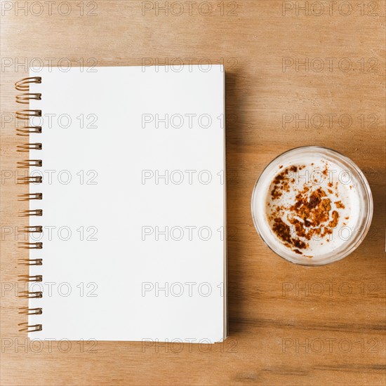 Closed white spiral notebook coffee glass with cocoa powder
