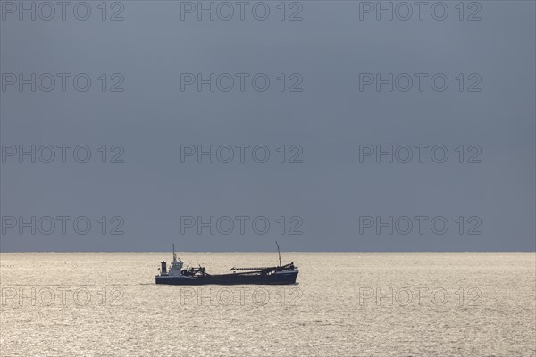 Dark clouds and sunlight over the North Sea plus freighter