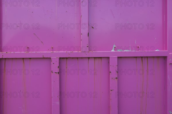 Pink painted metal container with rust stains