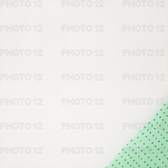 Polka dot green wrapped paper corner white background