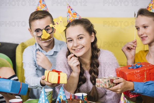 Happy friends holding props hand giving gifts smiling teenage girl