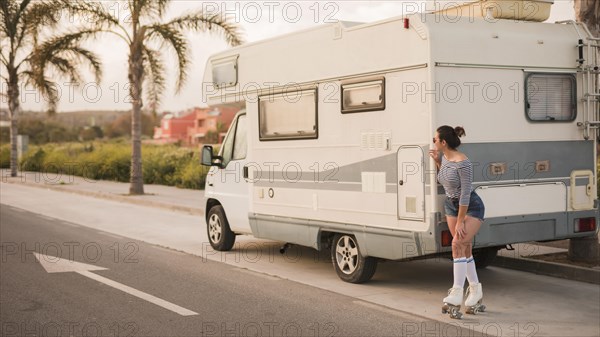 Female skater standing caravan road peeking