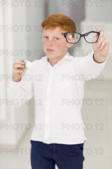 Freckle boy holding eyeglasses contact lenses container