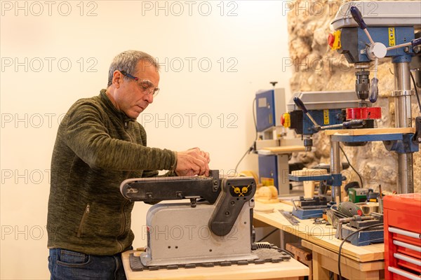 Man using a machine to sand a piece of wood in an artisan workshop