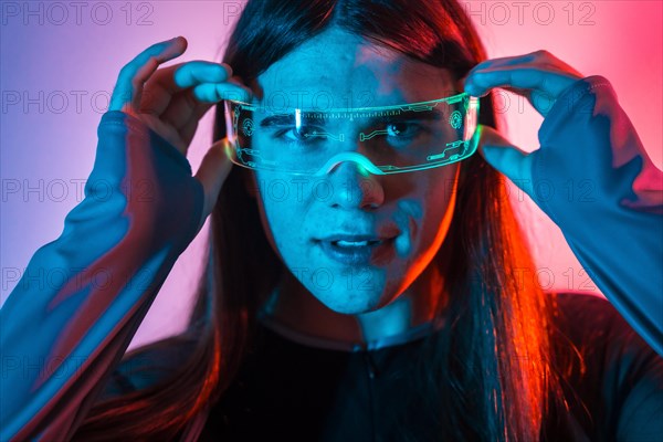 Futuristic studio portrait with neon lights of a non-binary person putting on augmented reality goggles