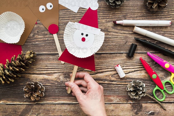 Elevated view woman s hand holding santa claus prop table