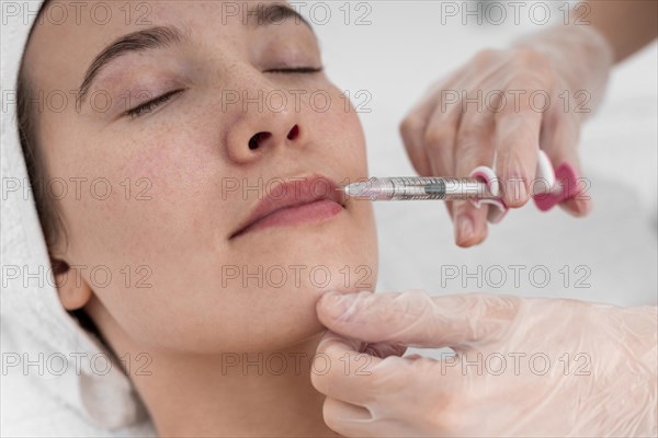 Beautician doing filler injection female client 2