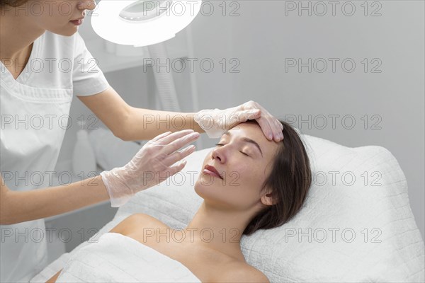Beautician with female client salon face care routine 2