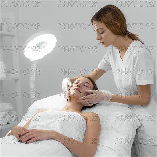 Beautician with female client salon face care routine 4