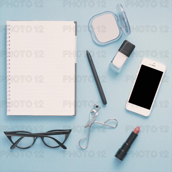 Smartphone with notebook cosmetics blue table