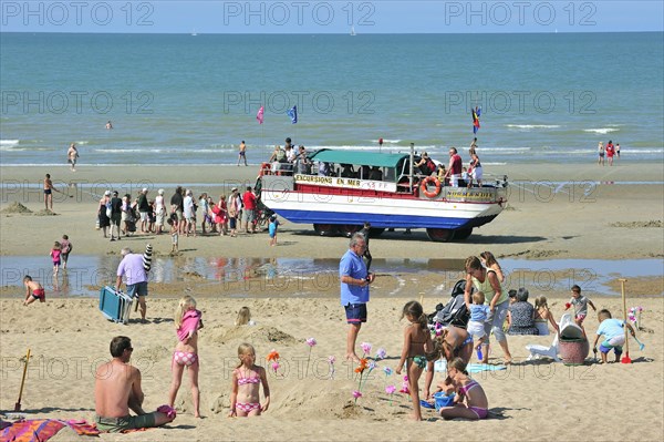 Sunbathers in summer sunbathing and amphibious excursion vehicle on beach along the North Sea coast at Koksijde