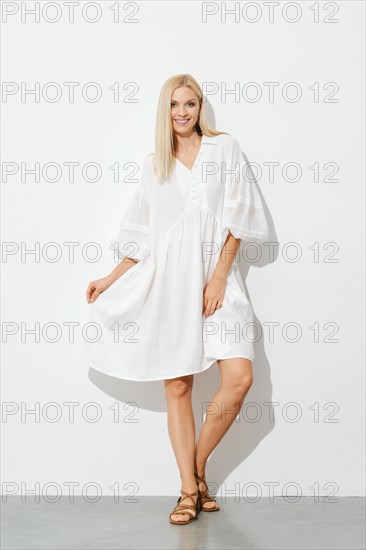 Portrait of happy stylish woman in white sundress indoors