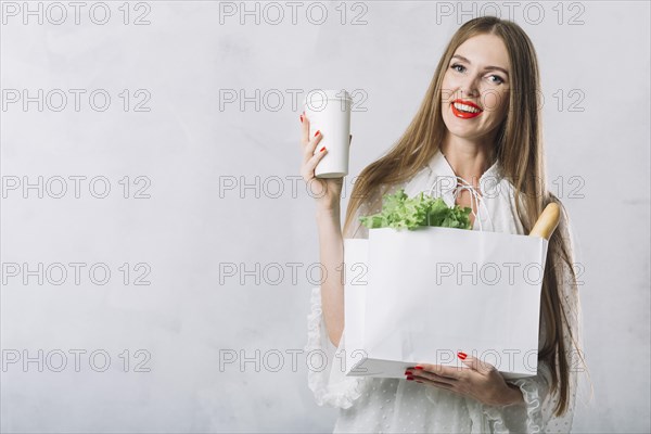 Beautiful young woman holding groceries bag