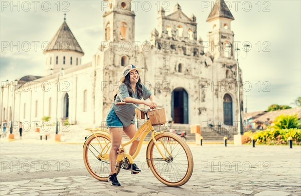 Lifestyle of a happy girl in hat on bicycle on the street. Granada