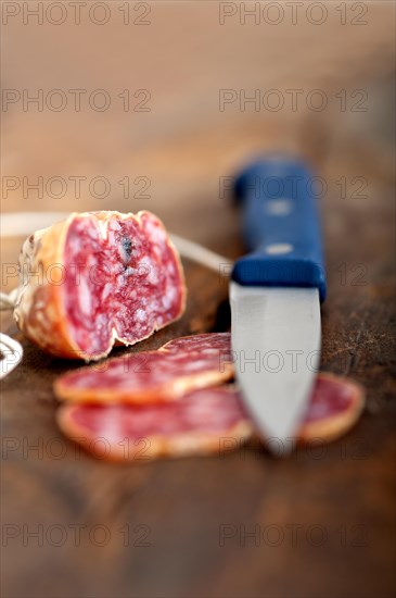 Slicing italian salame pressato pressed over old wood table