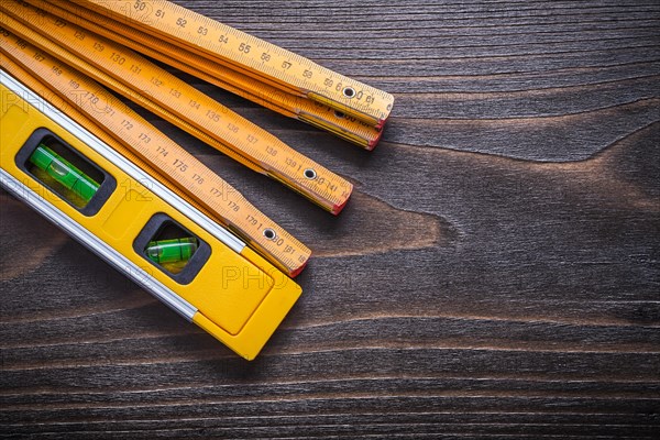 Horizontal view of yellow construction level with wooden metre on vintage wooden board maintenance concept