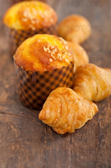 Fresh baked muffin and croissant mignon on old wood table