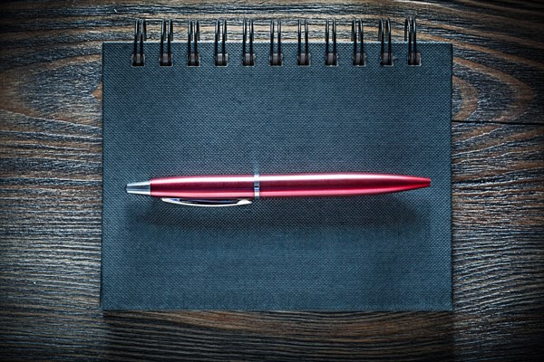 Black notebook pen on vintage wooden board top view