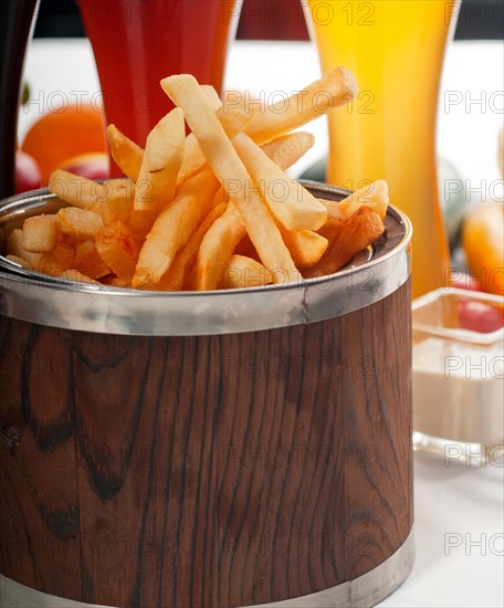 Fresh french fries on a wood bucket with selection of beers and fresh vegetables on background