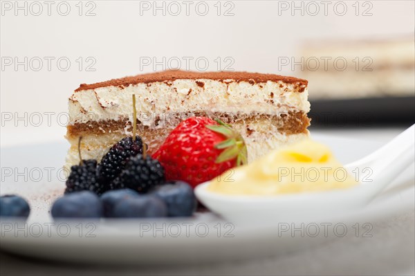 Classic Italian tiramisu dessert with berries and custartd pastry cream on side