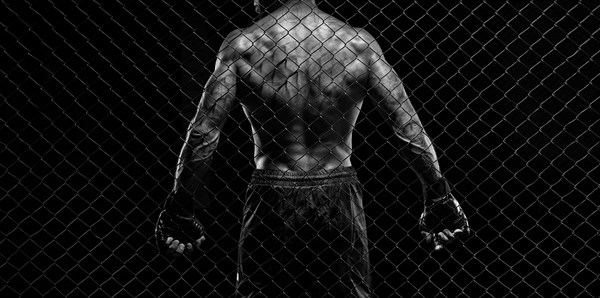 Black and white image of a man in a boxing cage. The concept of sports