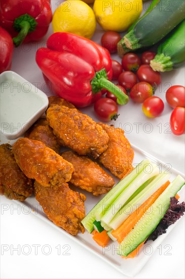 Classic buffalo chicken wings served with fresh pinzimonio and vegetables on background