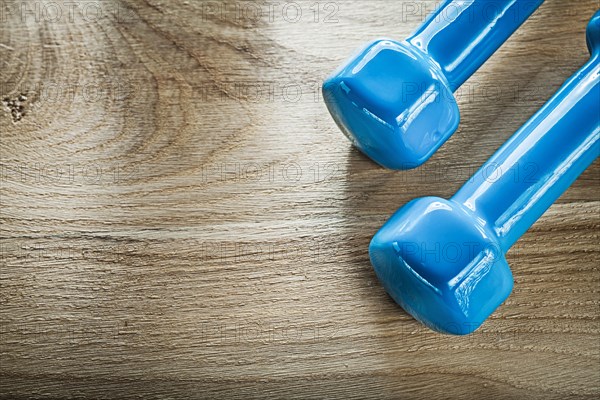 Blue dumbbell weights on wooden board fitness concept