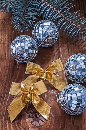 Golden bows and Christmas disco baubles with Christmas tree branch on an old wooden board