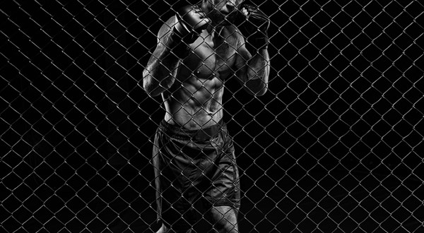 Black and white image of a man in a boxing cage. The concept of sports