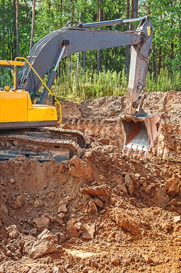 Excavator excavating clay soil on a construction site in the forest