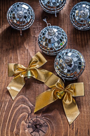 Two golden bows and Christmas disco mirror balls on an old wooden board