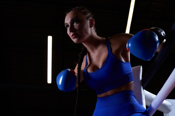 Powerful charged girl stands in the corner of the ring and is ready to explode in the next round. The concept of wrestling and boxing. Mixed media