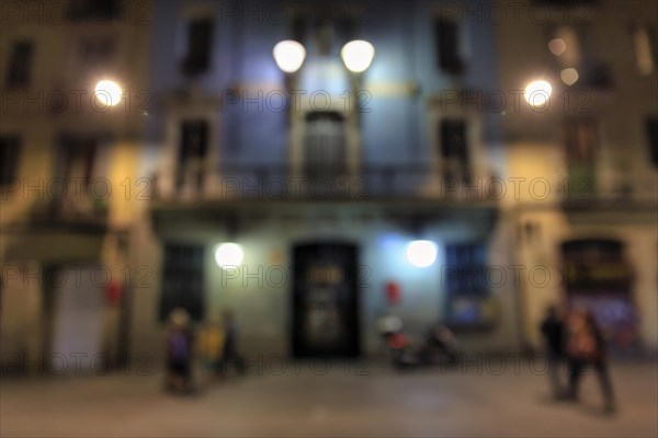 Passers-by in front of illuminated house facade at night