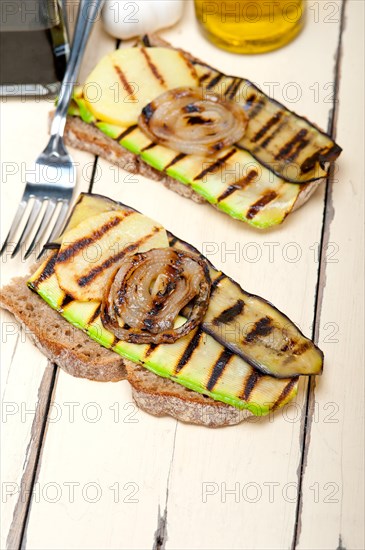 Grilled vegetables on rustic bread over wood table
